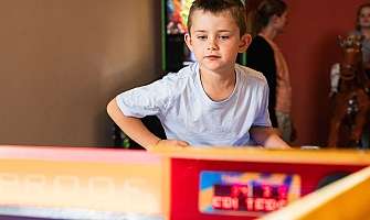 Un garçon se concentre en jouant à une table de air hockey.