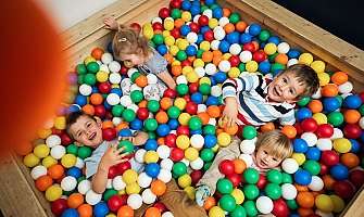 Quatre enfants jouent joyeusement dans une piscine à balles colorée.