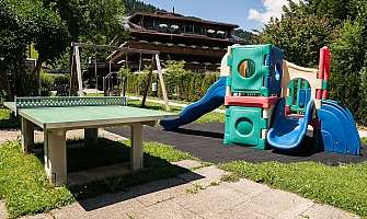 Jouets colorés et table de ping-pong dans un jardin.