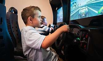 Deux enfants jouent à des machines de jeux de course.