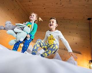 Zwei Kinder in Schlafanzügen springen fröhlich auf einem Bett.