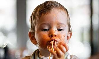 Un enfant souriant est allongé entre des balles colorées.