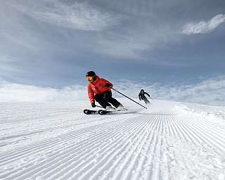Deux skieurs descendent sur une piste fraîchement préparée.