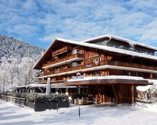 Ein Holzhaus im Schnee mit Bergen im Hintergrund.