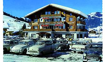 Un hôtel dans la neige avec de nombreuses voitures garées.