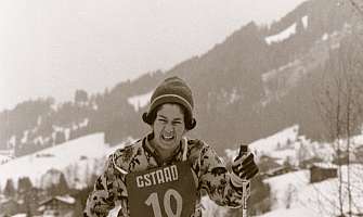 Femme avec des skis et un numéro de départ dans un paysage enneigé.