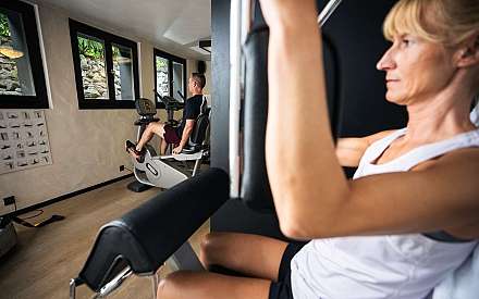 Une femme s'entraîne sur un appareil, un homme sur un ergomètre.