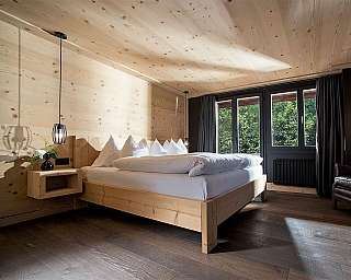 Cozy bedroom with wooden decor and large windows.