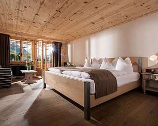 Cozy bedroom with wooden ceiling and balcony view.