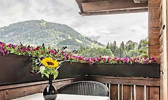 Cozy balcony with table, chairs, and a view of the mountains.