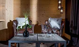 Two leather armchairs and a table with flowers and glasses.