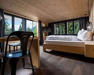 Bright bedroom with wooden floor and large windows.