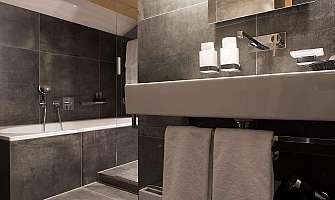 Elegant bathroom with dark tiles and modern fittings.