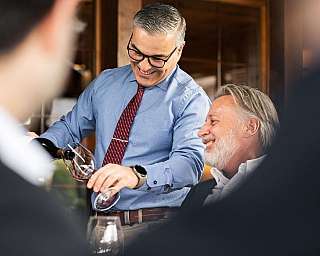 Ein Kellner schenkt Wein in Gläser für Gäste ein.